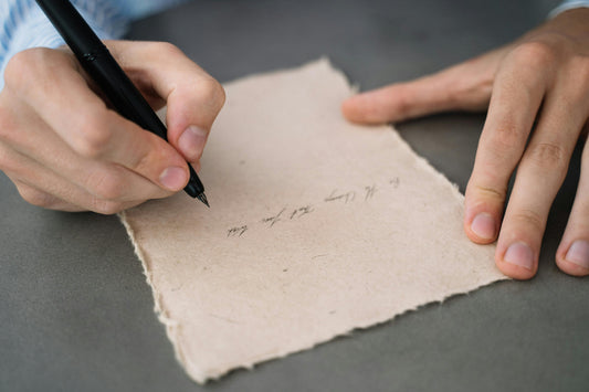 a hand holding a pen and writing a note