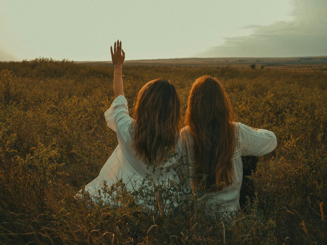 Two girls in a field watching the sunset