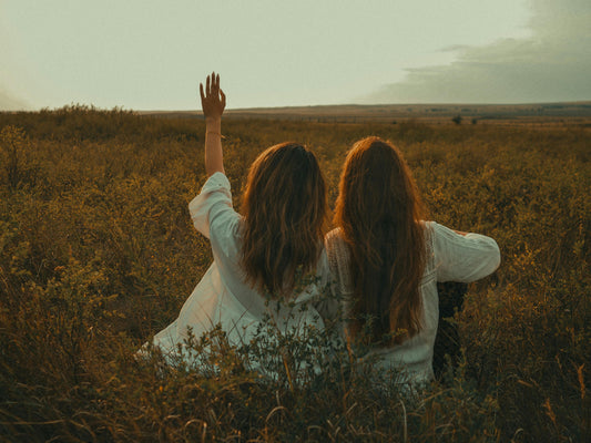 Two girls in a field watching the sunset