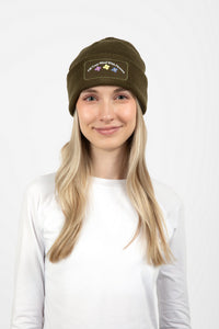 Woman wearing olive green beanie with Fill Your Mind With Flowers on the front