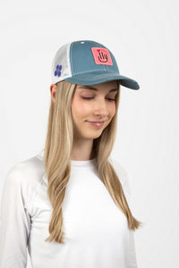 Woman wearing a light blue baseball cap with a pink ILY logo - Side view